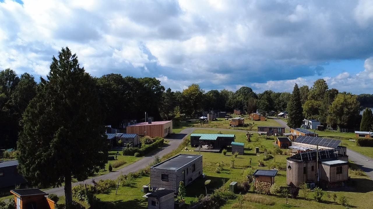 Die Siedlung von oben: Tiny Houses auf großzügigen Stellplätzen zwischen Bäumen und Wegen